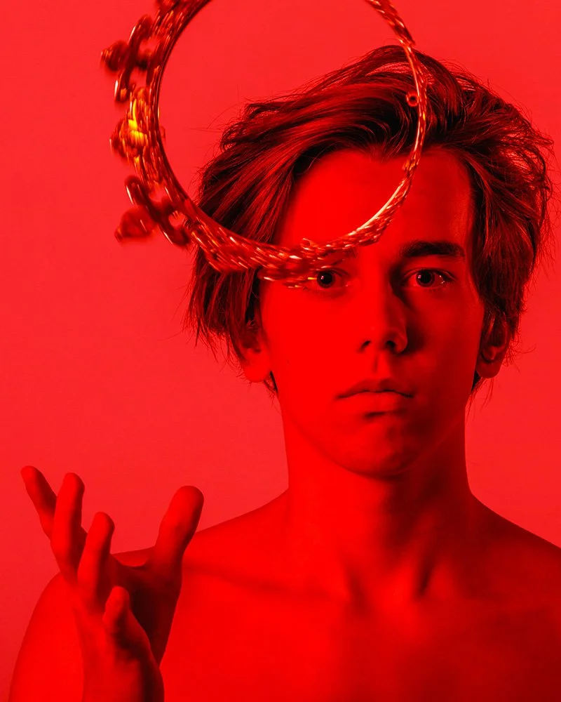 Young man spinning gold crown in red light