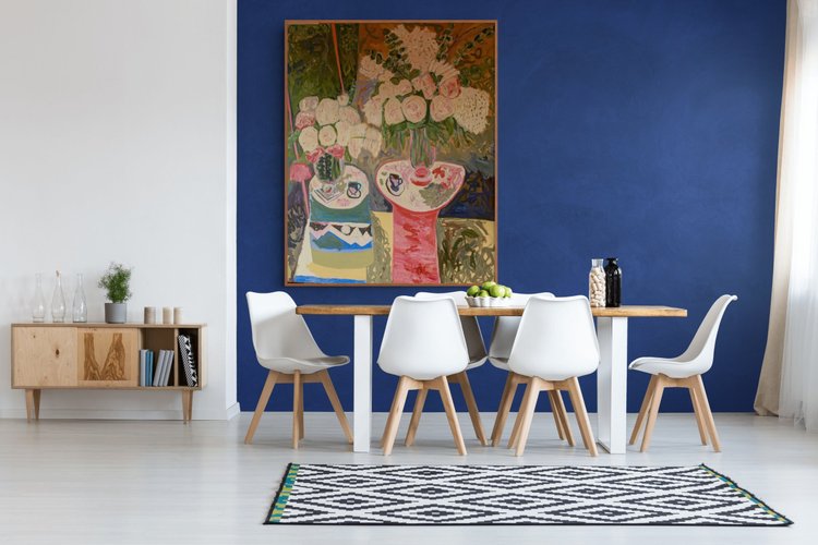 Room visualization of a floral oil painting by Erin Smith in a dining room with a blue wall and white chairs