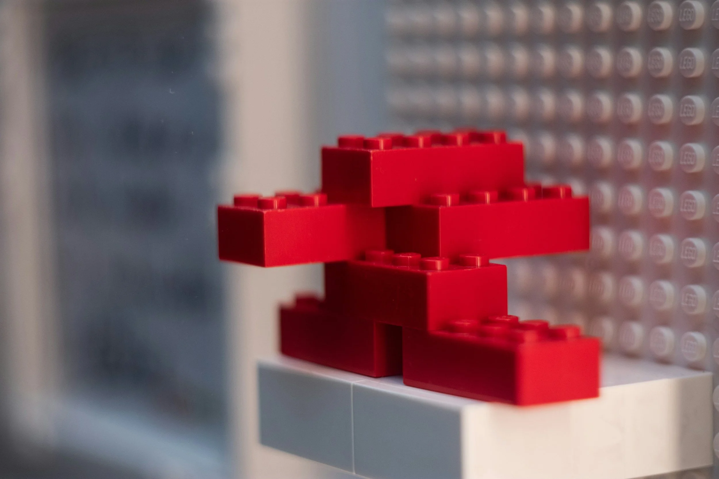 Red LEGO bricks arranged on a white and light gray LEGO baseplate.