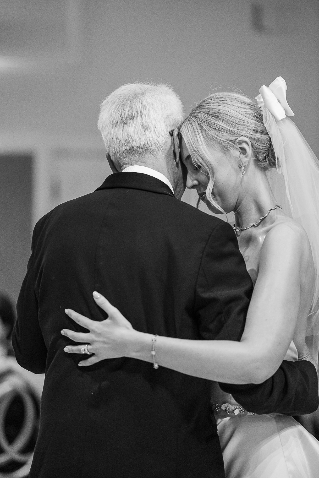 A black-and-white photo of a bride and an older man, possibly her father, sharing a dance at a wedding. They are close with their foreheads touching at Cavallo Point in Sausalito, CA.