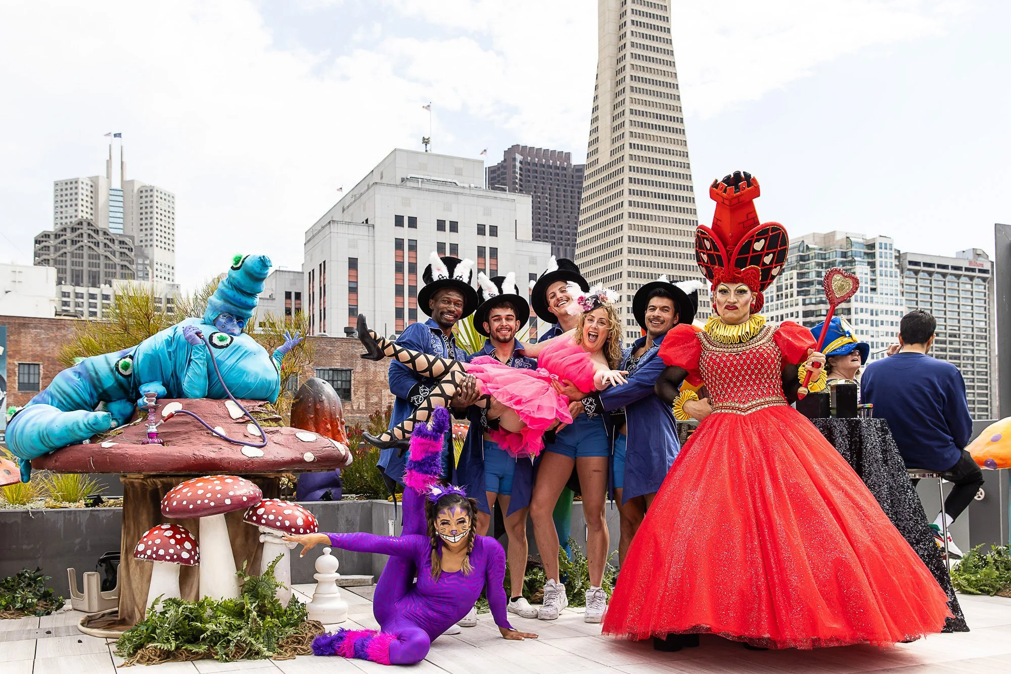 Group of performers in colorful costumes at a parade or festival in an urban setting, with tall buildings in the background.