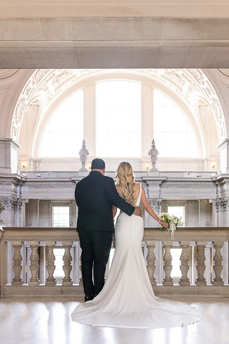 Bride and groom at the balustrade beneath the arched window at San Francisco City Hall