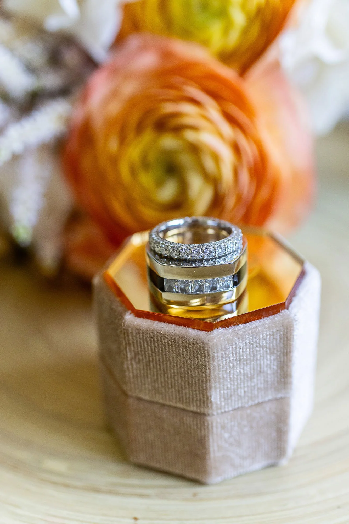 A ring with diamonds resting on a jewelry box, with a blurred background of a multicolored flower at the Beach and Tennis Club in Pebble Beach, CA.