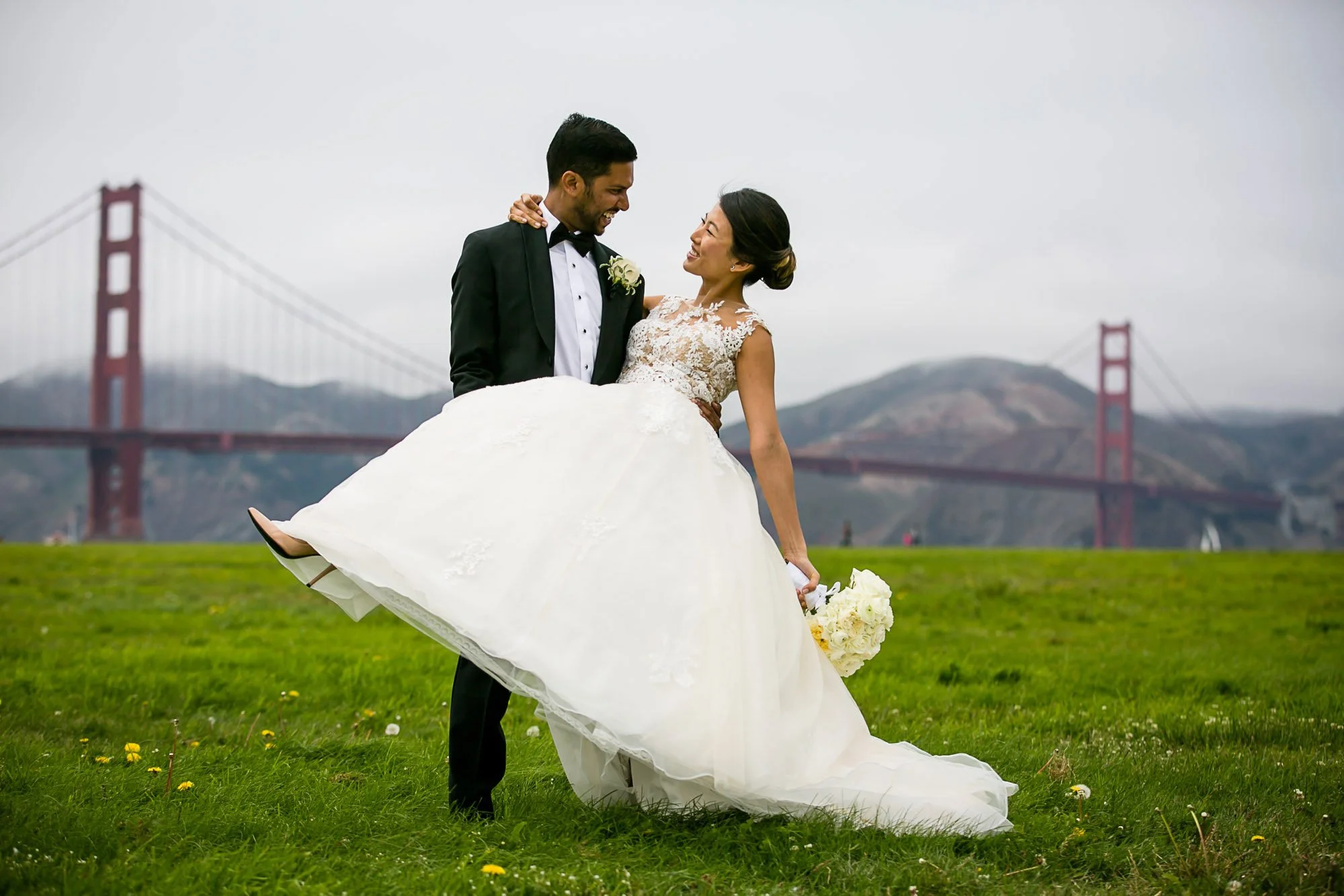 Bride's dress catching the wind with the Golden Gate Bridge behind them