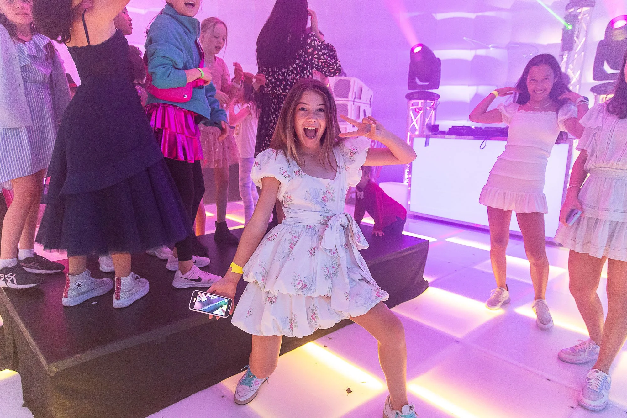Bat mitzvah girl dancing with friends on a lit dance floor at her reception