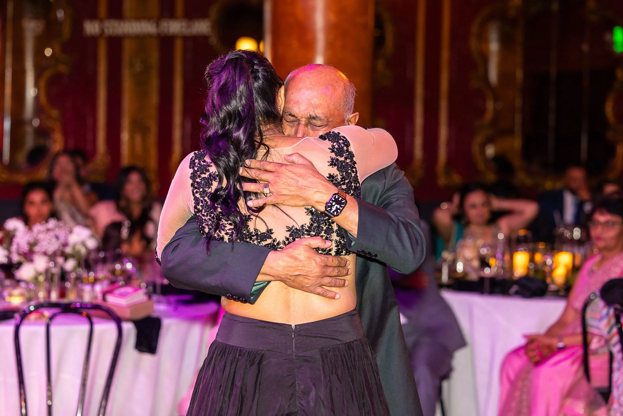 A couple dancing closely at a formal event with women sitting at tables in the background at the Great American Music Hall in San Francisco.
