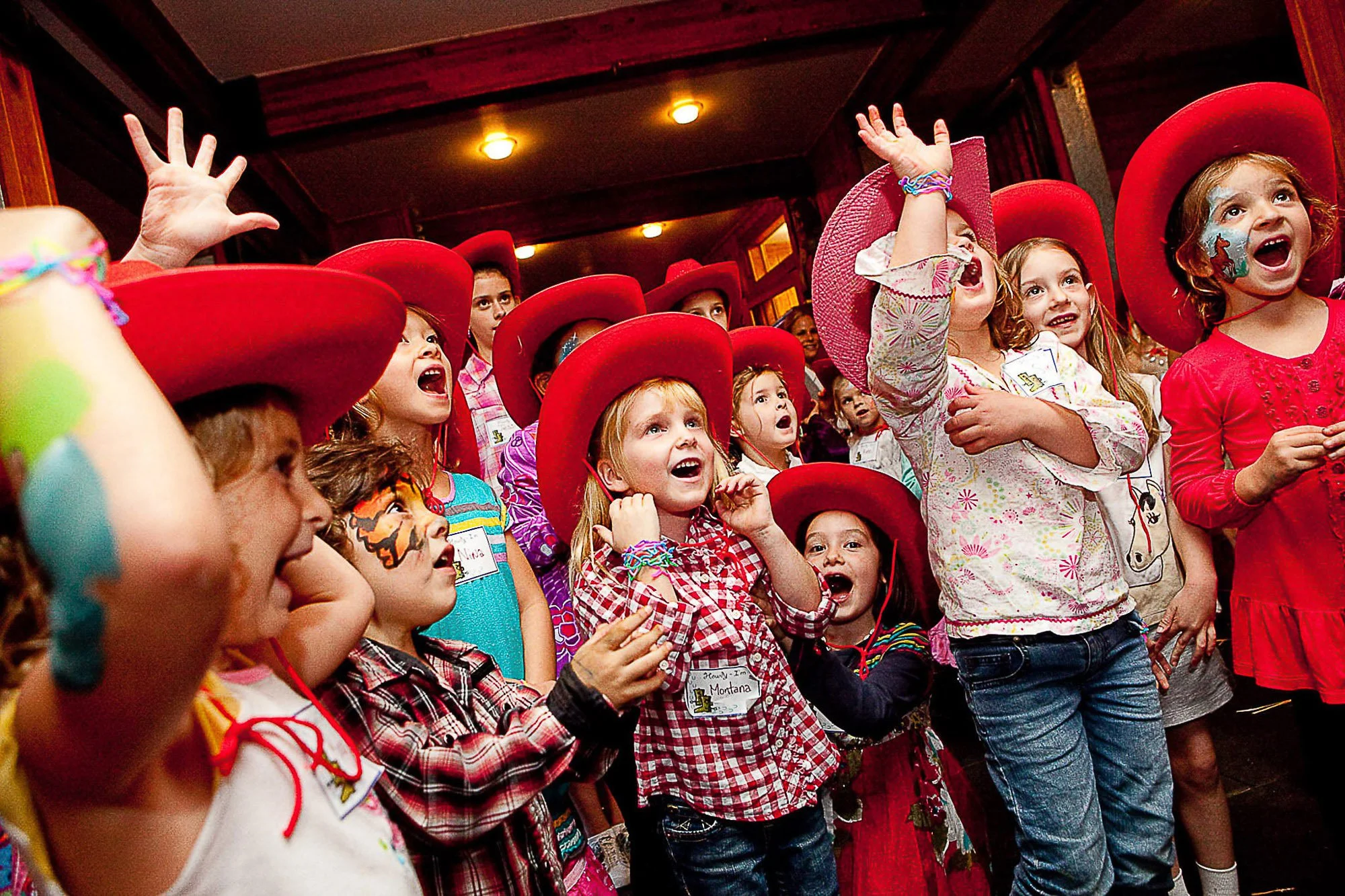Children in cowboy hats reaching up at a themed birthday party