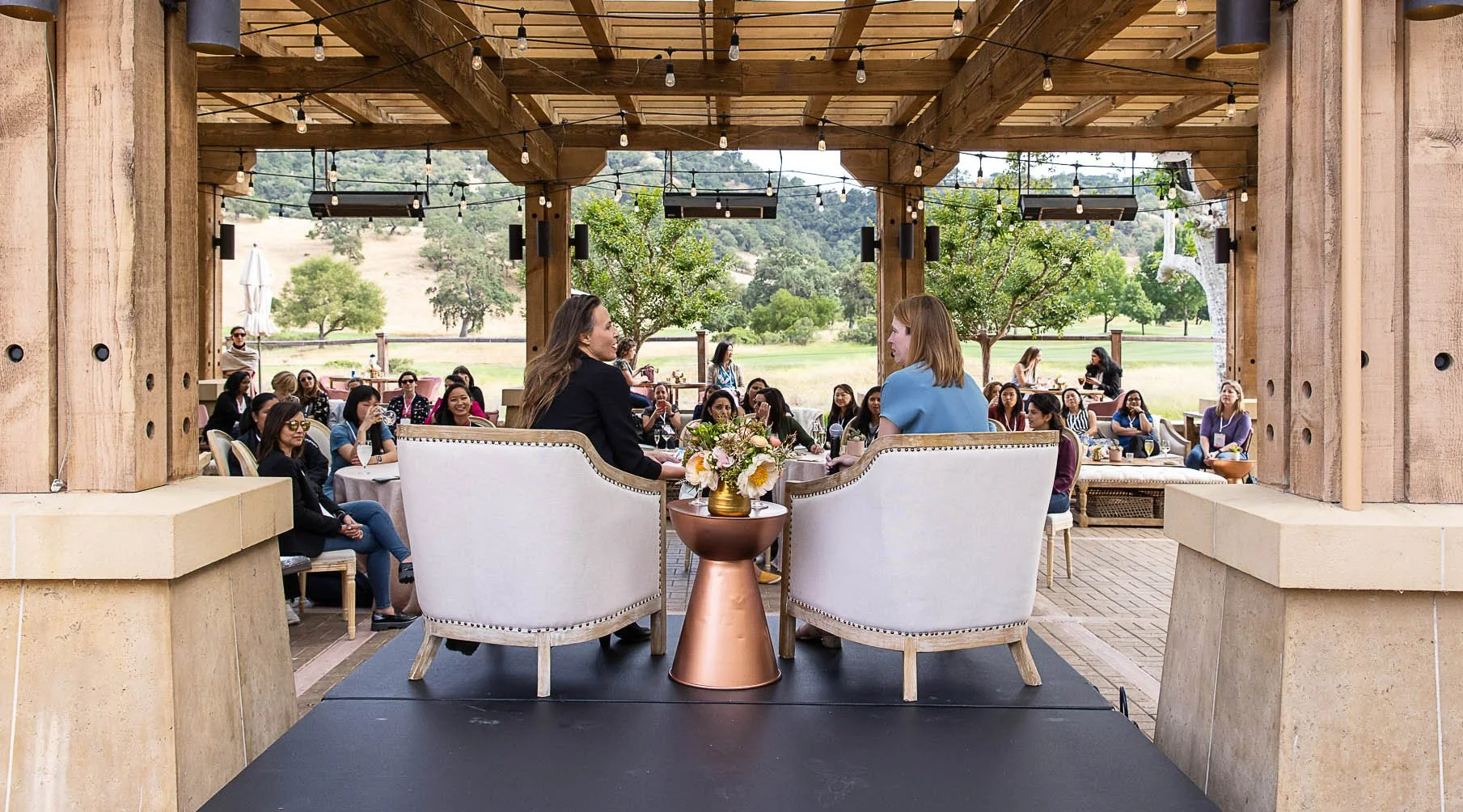 Two speakers in conversation during an outdoor leadership retreat session in wine country