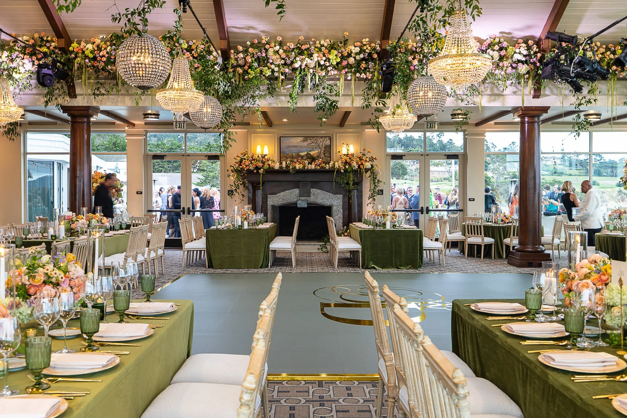 Elegant banquet hall decorated with floral arrangements, chandeliers, and table settings for a wedding reception at the Beach and Tennis Club in Pebble Beach, CA.
