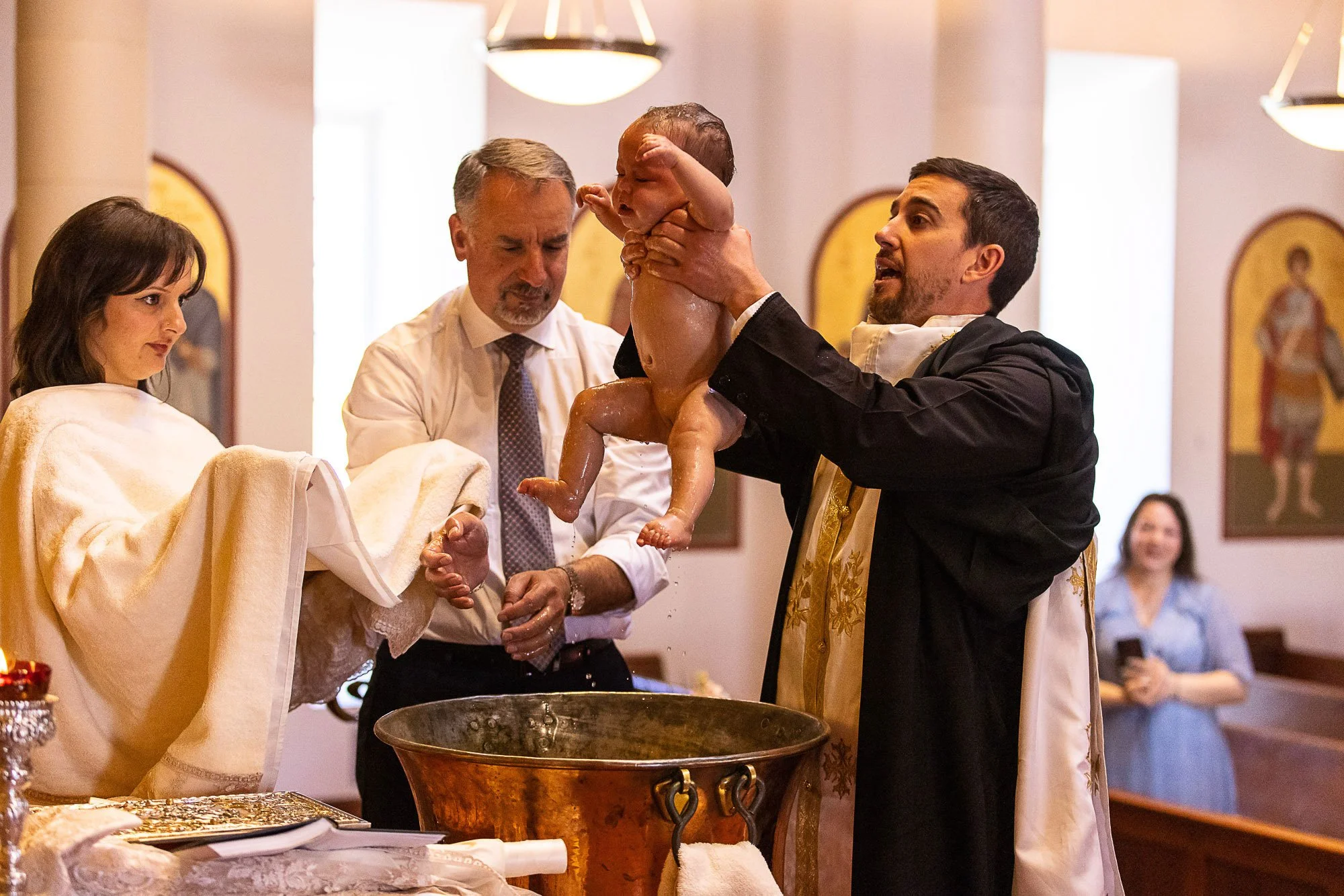 Priest lifting a baby above the font during a baptism