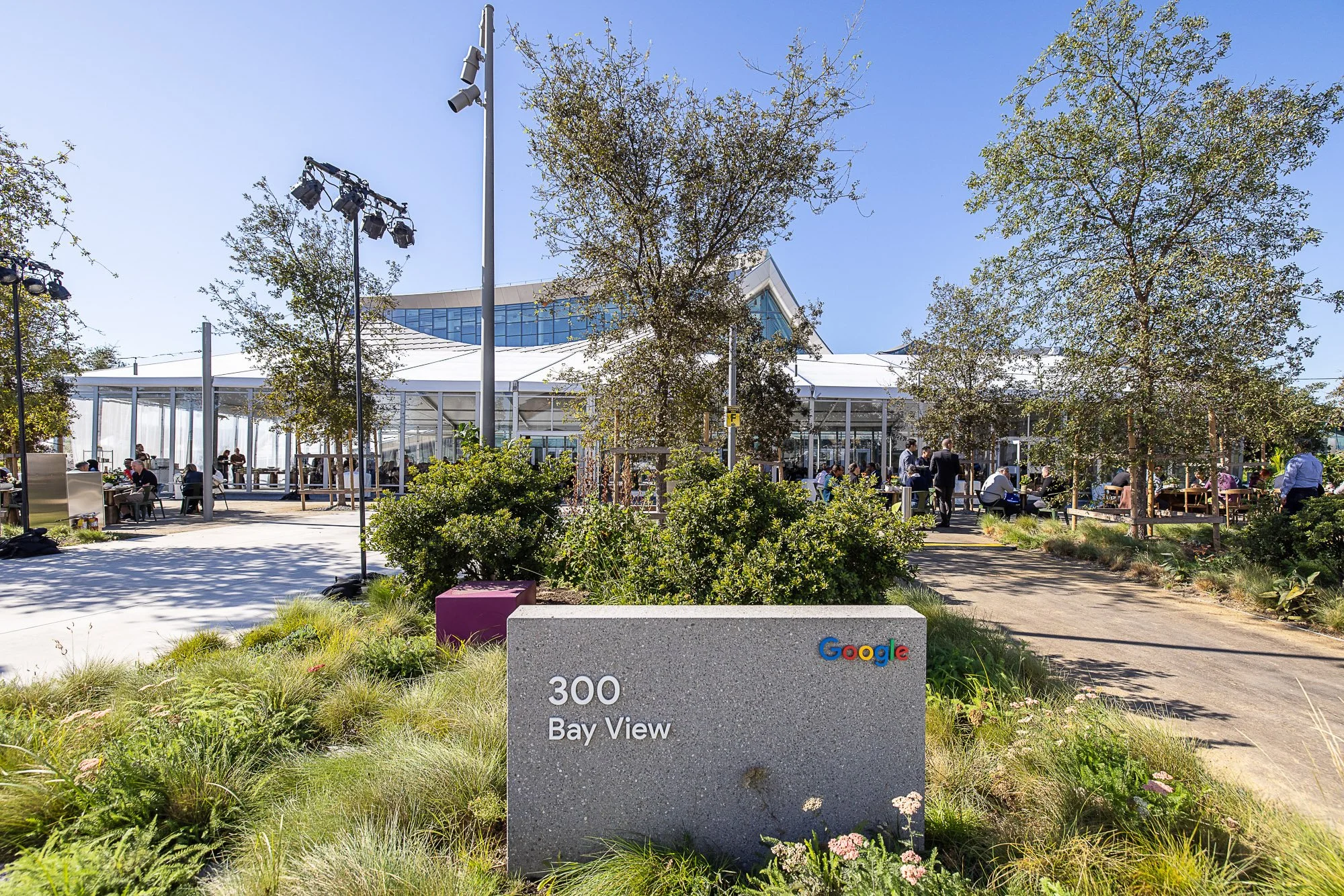 Google sign with '300 Bay View' text in front of a modern building with outdoor seating and trees