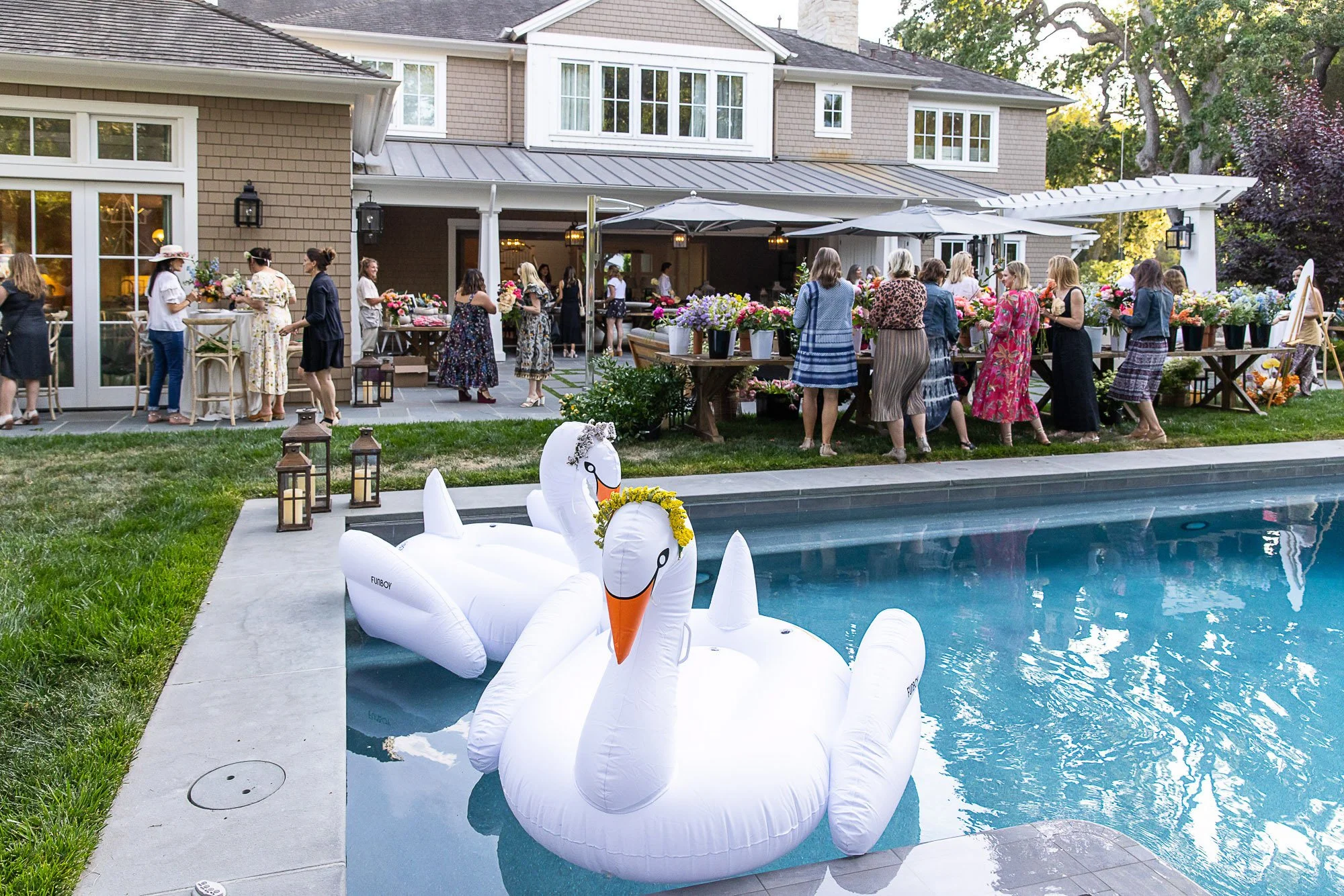 Large inflatable swan decorated as a white swan floating in a swimming pool at an outdoor gathering.
