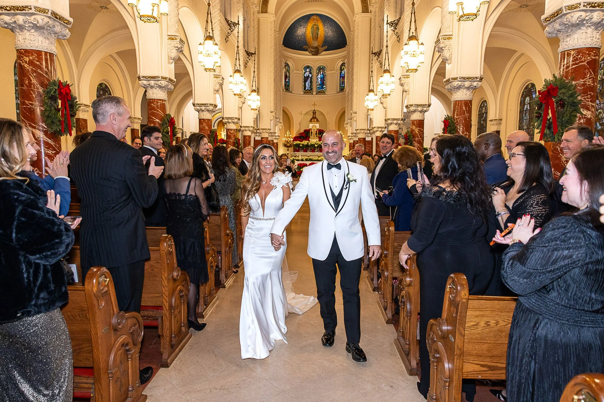 Bride and groom walking back up the aisle as guests applaud at their San Francisco church ceremony