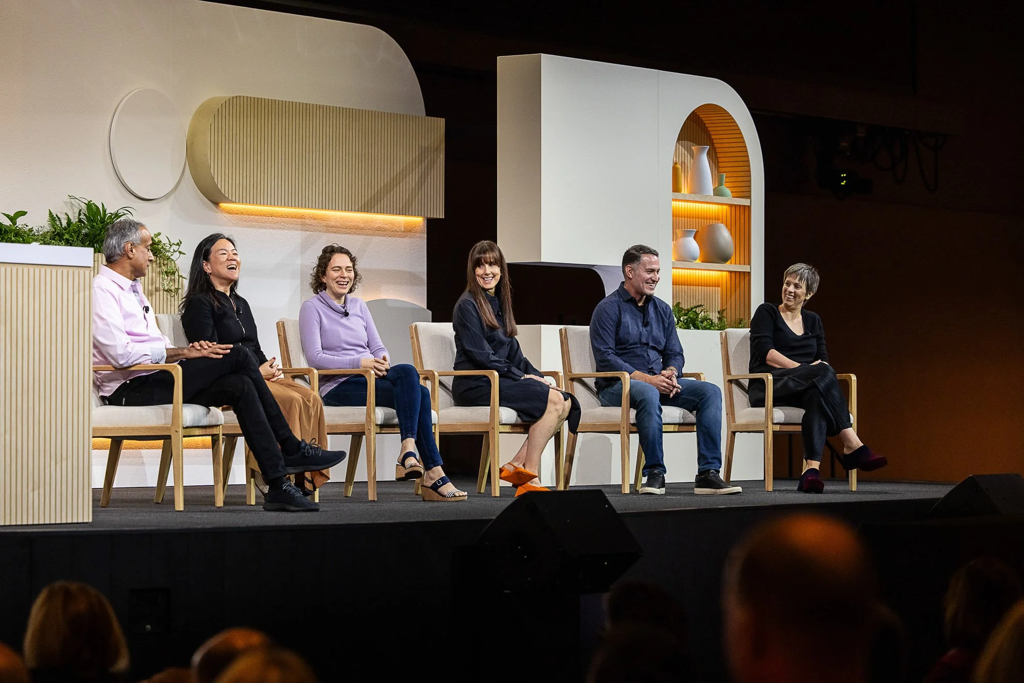 Six panelists seated on stage during a conference session