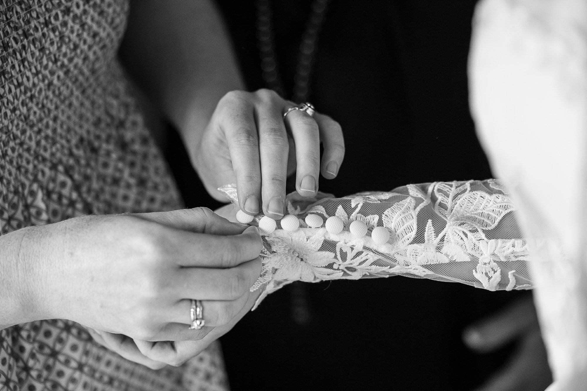 Close-up of hands of a woman wearing rings, holding a lace garter with pom-poms during a wedding  at Cavallo Point in Sausalito, CA.