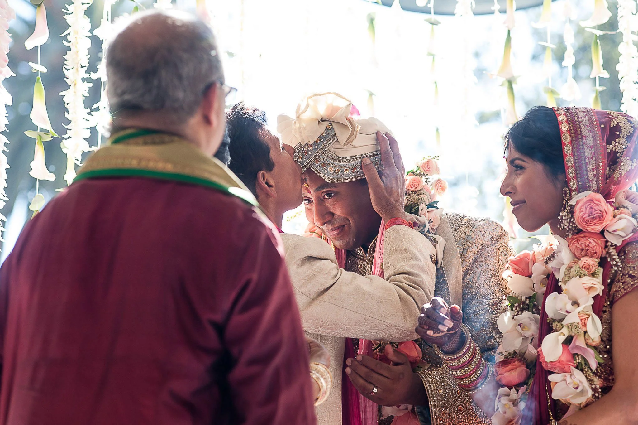 A traditional Indian wedding ceremony with the bride and groom exchanging vows, surrounded by family members and floral decorations.