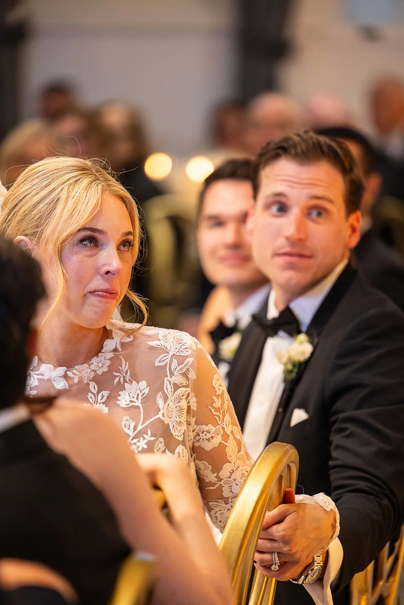 A woman with blonde hair wearing a lace dress and a man in a tuxedo at what appears to be a formal event or wedding reception at Cavallo Point in Sausalito, CA.