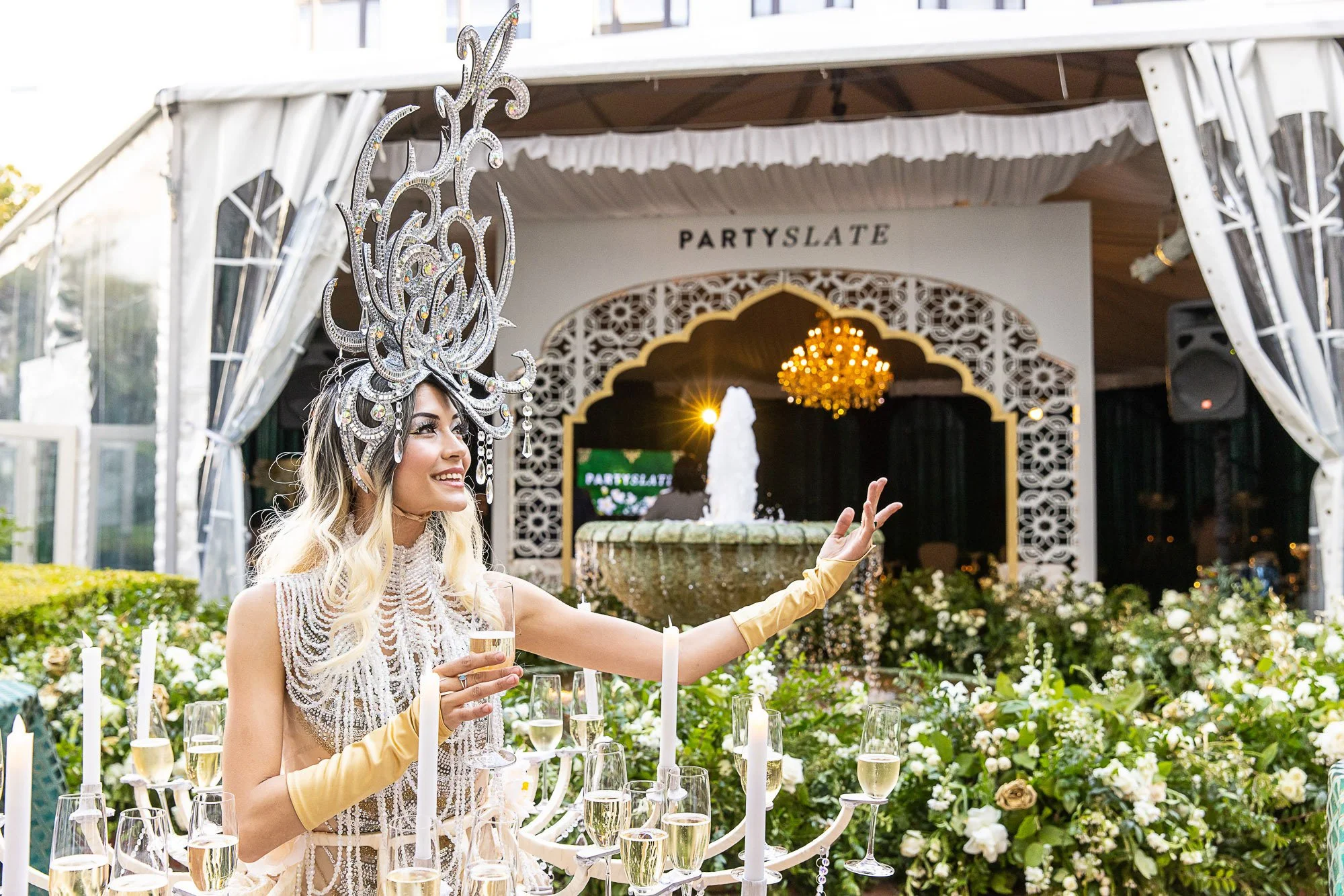 Guest in a crystal headpiece raising a champagne glass at a wedding industry party