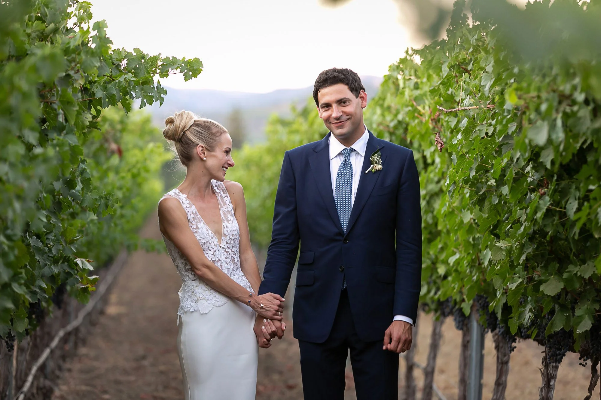 Bride and groom holding hands in the vineyard rows at Beaulieu Garden, Napa Valley