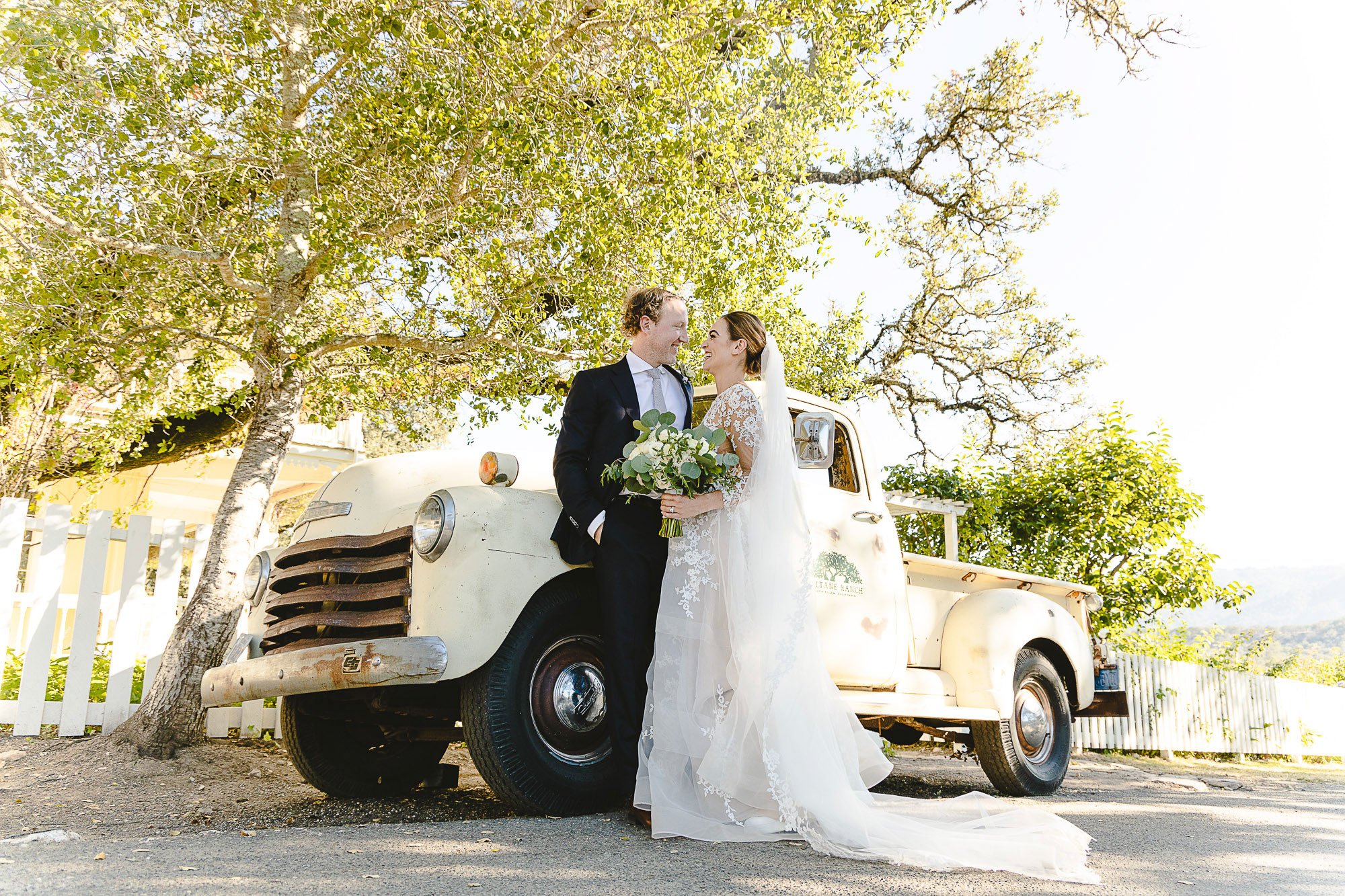 Bride and groom kissing beside a vintage white truck at Beltane Ranch, Sonoma