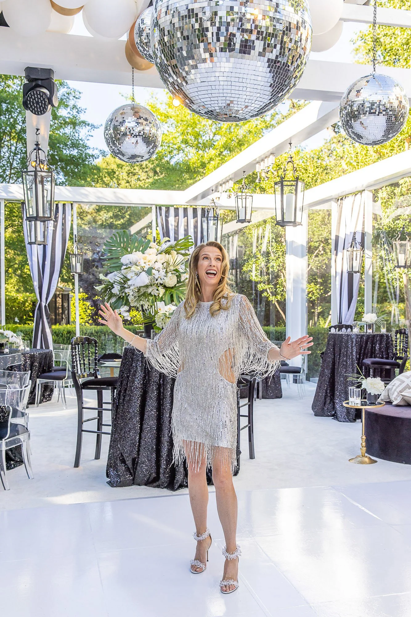 Guests dancing under stage lighting and a disco ball at a 50th birthday party