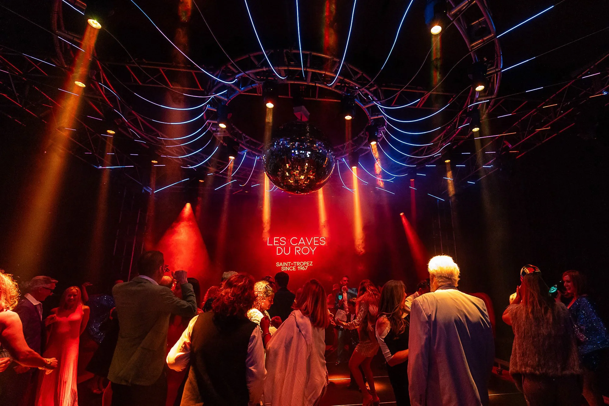 Guests dancing under stage lighting and a disco ball at a 50th birthday party