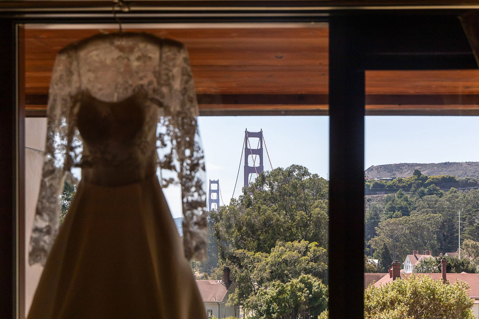 View of the Golden Gate Bridge through a window with a lace dress hanging in the foreground at Cavallo Point in Sausalito, CA.