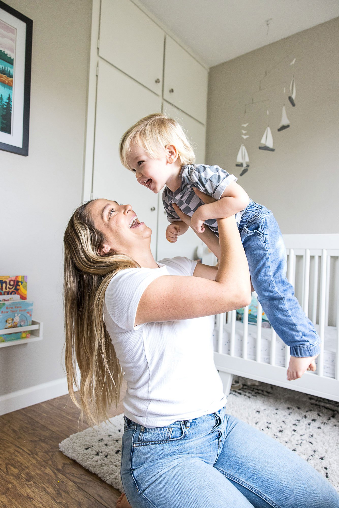 Mother lifting her toddler in the air in his nursery