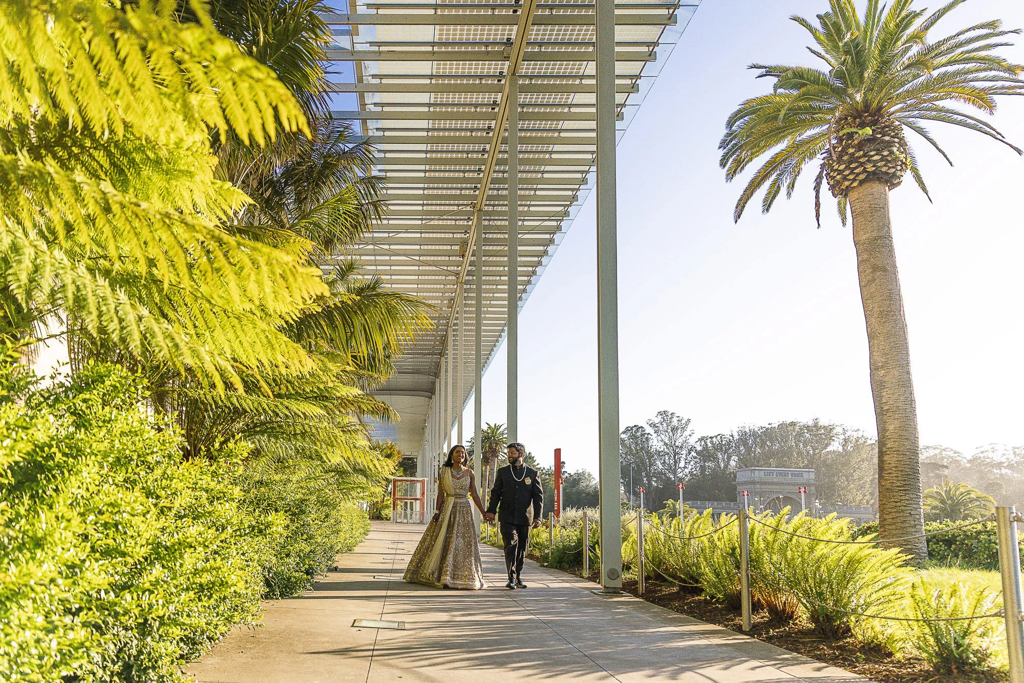 Bride and groom walking the colonnade at the California Academy of Sciences in Golden Gate Park