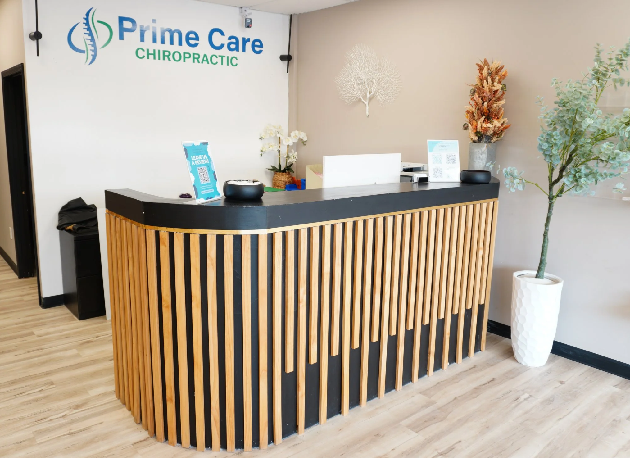 Reception desk at Prime Care Chiropractic with decorative plants and wall art.