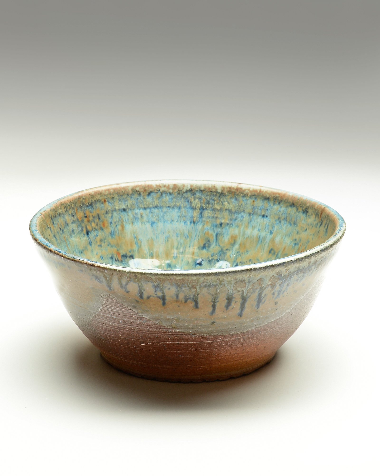 A ceramic bowl with a glazed, speckled blue and beige interior and a reddish-brown, unglazed exterior.