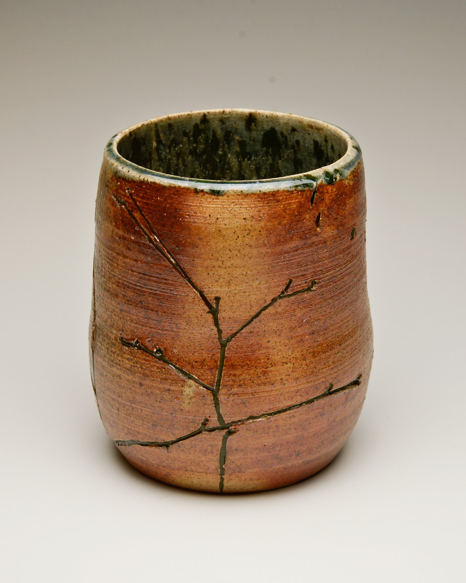 Ceramic vase with a crackled surface and black decorative branches.