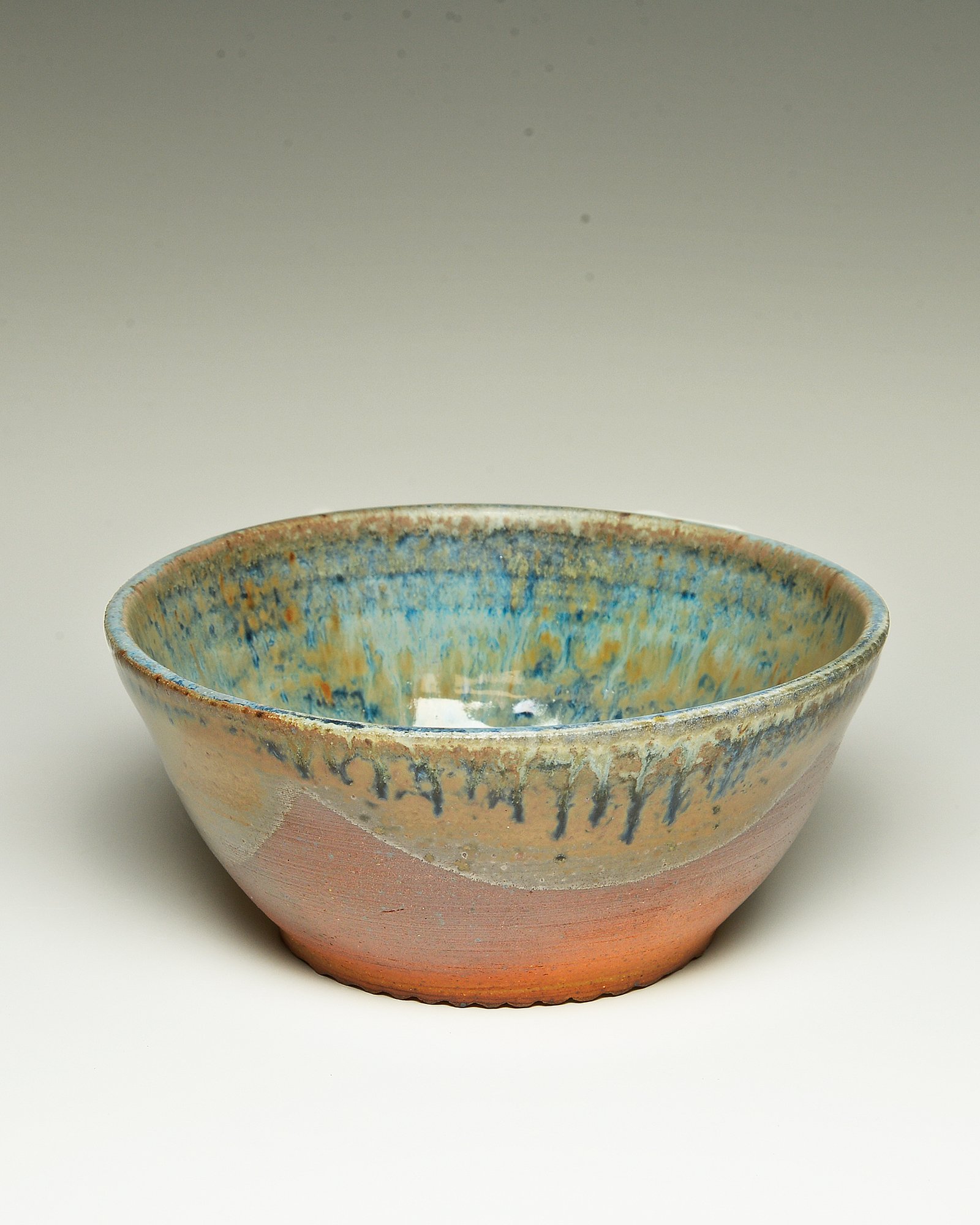 A ceramic bowl with a textured, colorful glaze on the interior and a plain, reddish exterior.