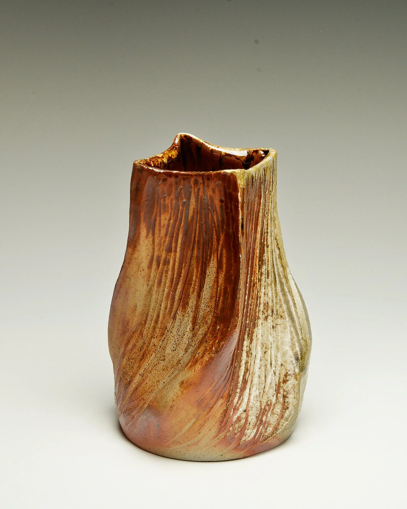 A ceramic vase with swirling patterns in shades of brown, beige, and cream, with a textured, organic shape and an asymmetrical opening at the top.