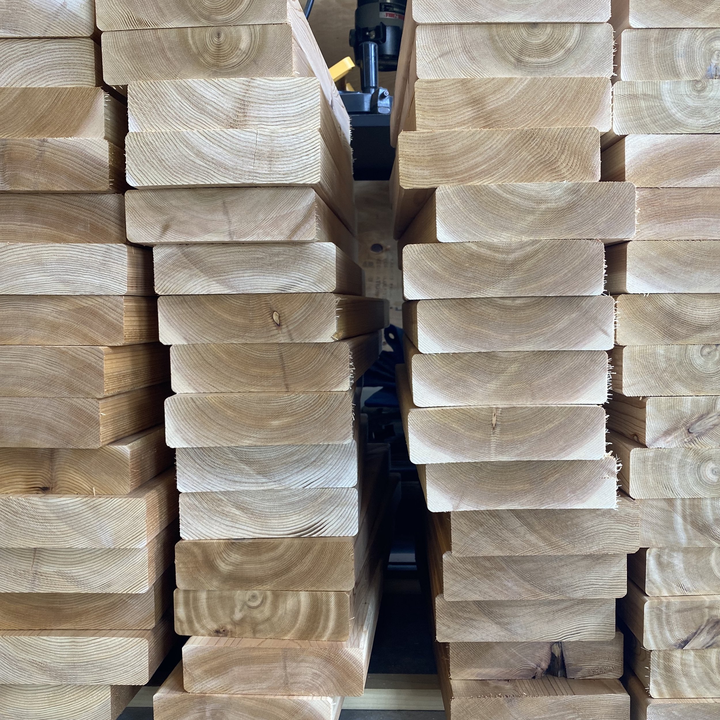Stacked cut wooden beams or planks in a workshop.