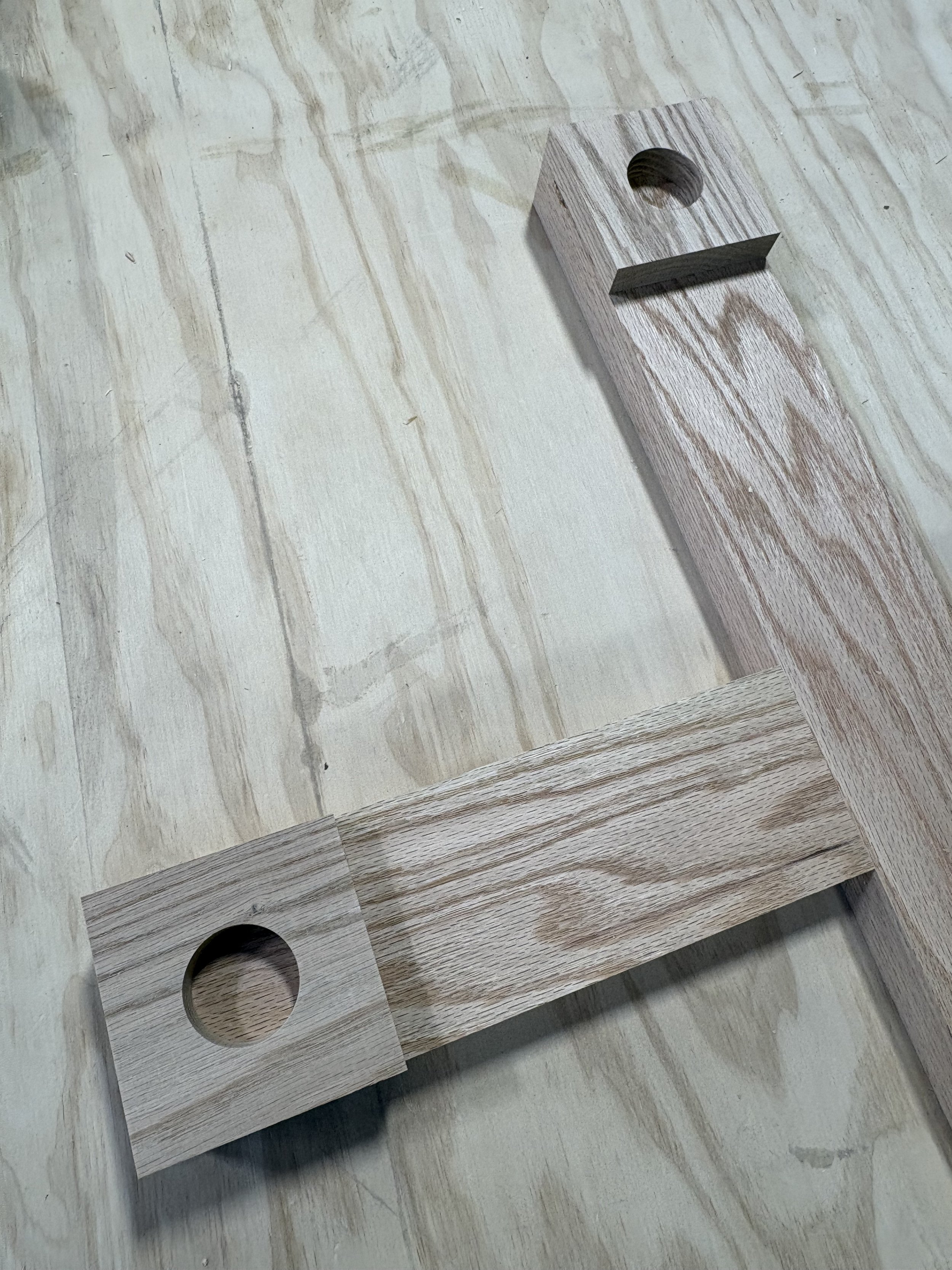 A close-up view of a wooden chessboard with circular holes for the pieces, on a wooden surface.