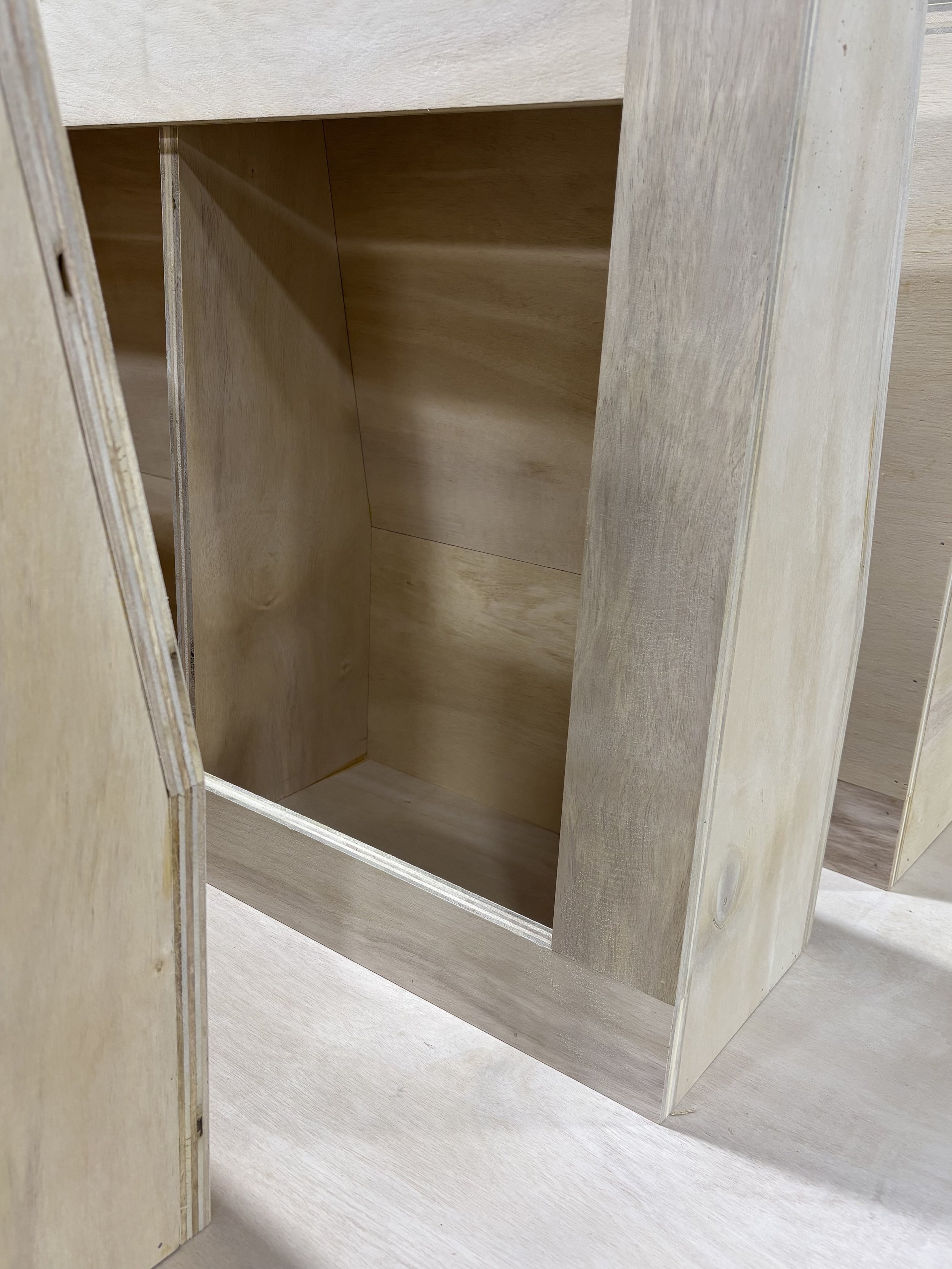 Empty unfinished wooden cabinet or shelving unit with light-colored wood finish.
