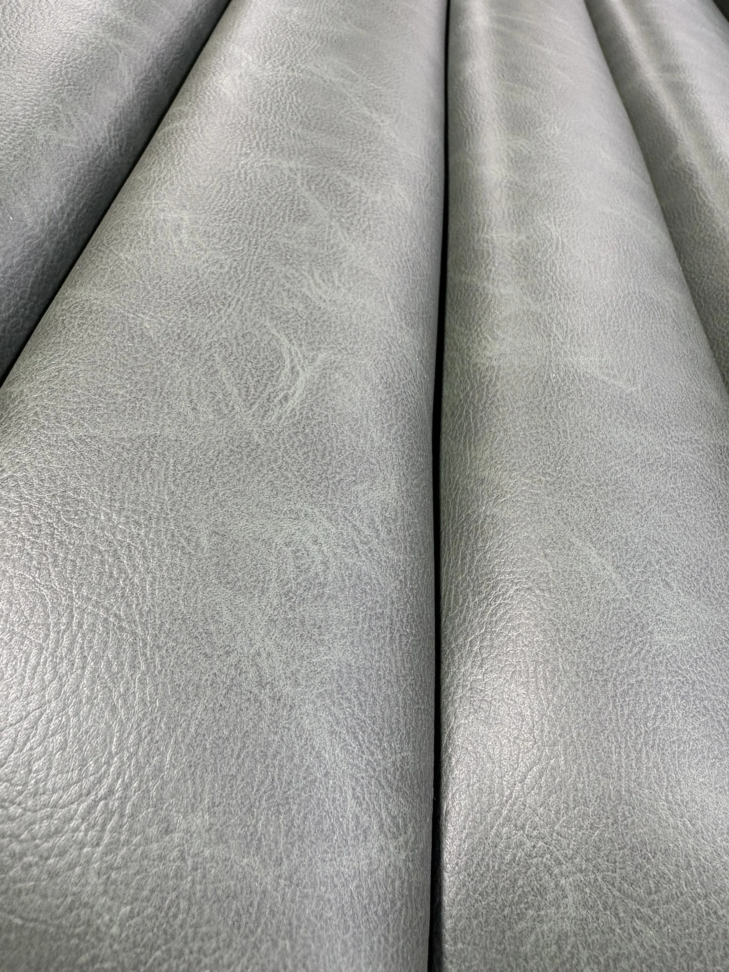 Close-up of two textured, gray, upholstered cushions or seats with a central black line between them.