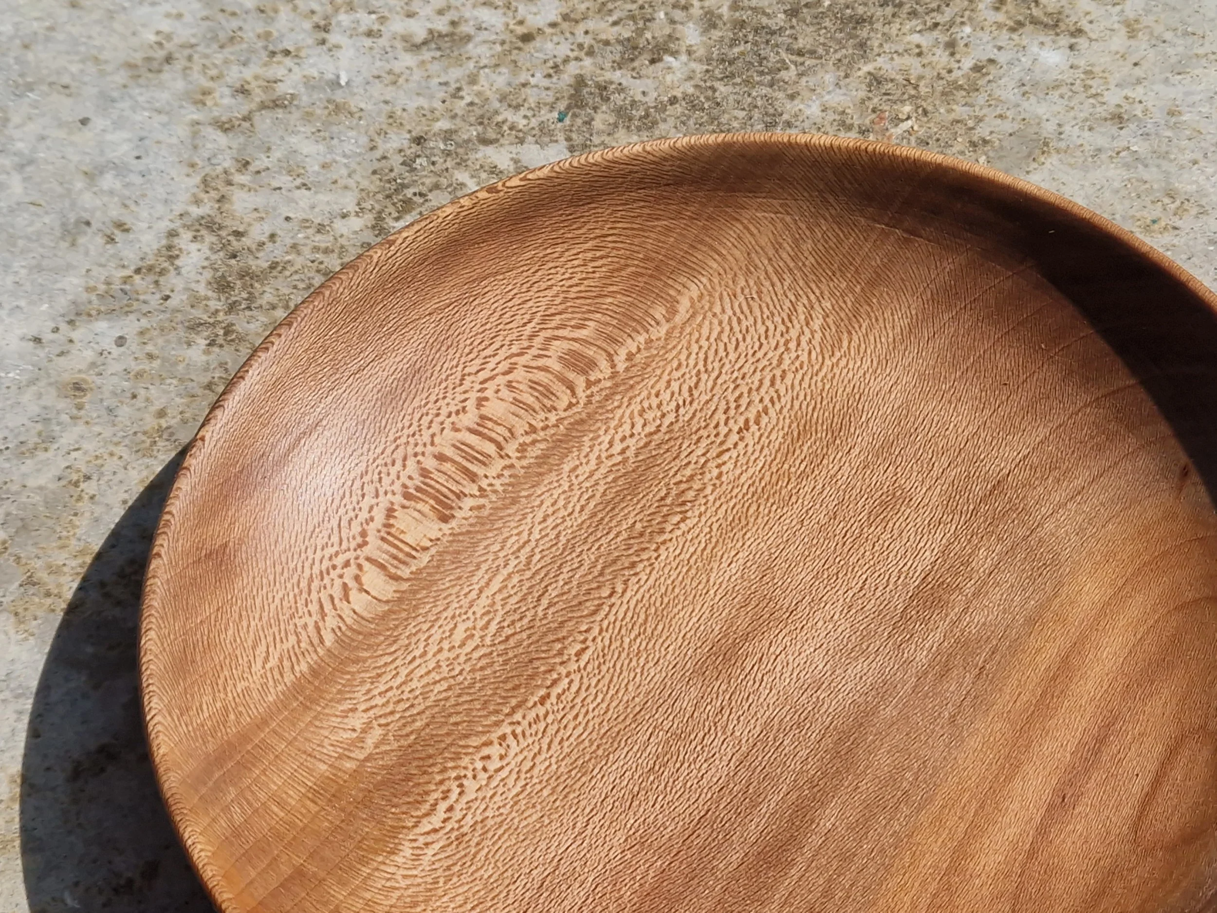 Une assiette en bois claire sur une surface en pierre, visible dans le bas de l'image.