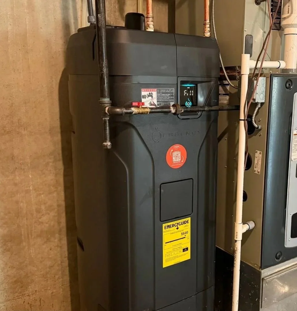 A black Essency electric water heater installed in the basement utility area of a Kansas City home.