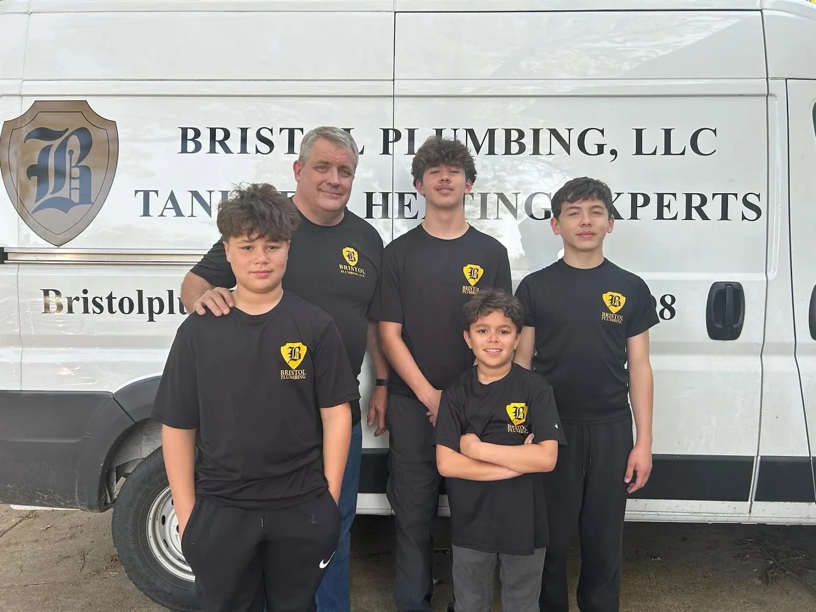 Bristol Plumbing owner, Mike Covington, with his four sons standing in front of a white van with 'Bristol Plumbing, LLC' logo and text.