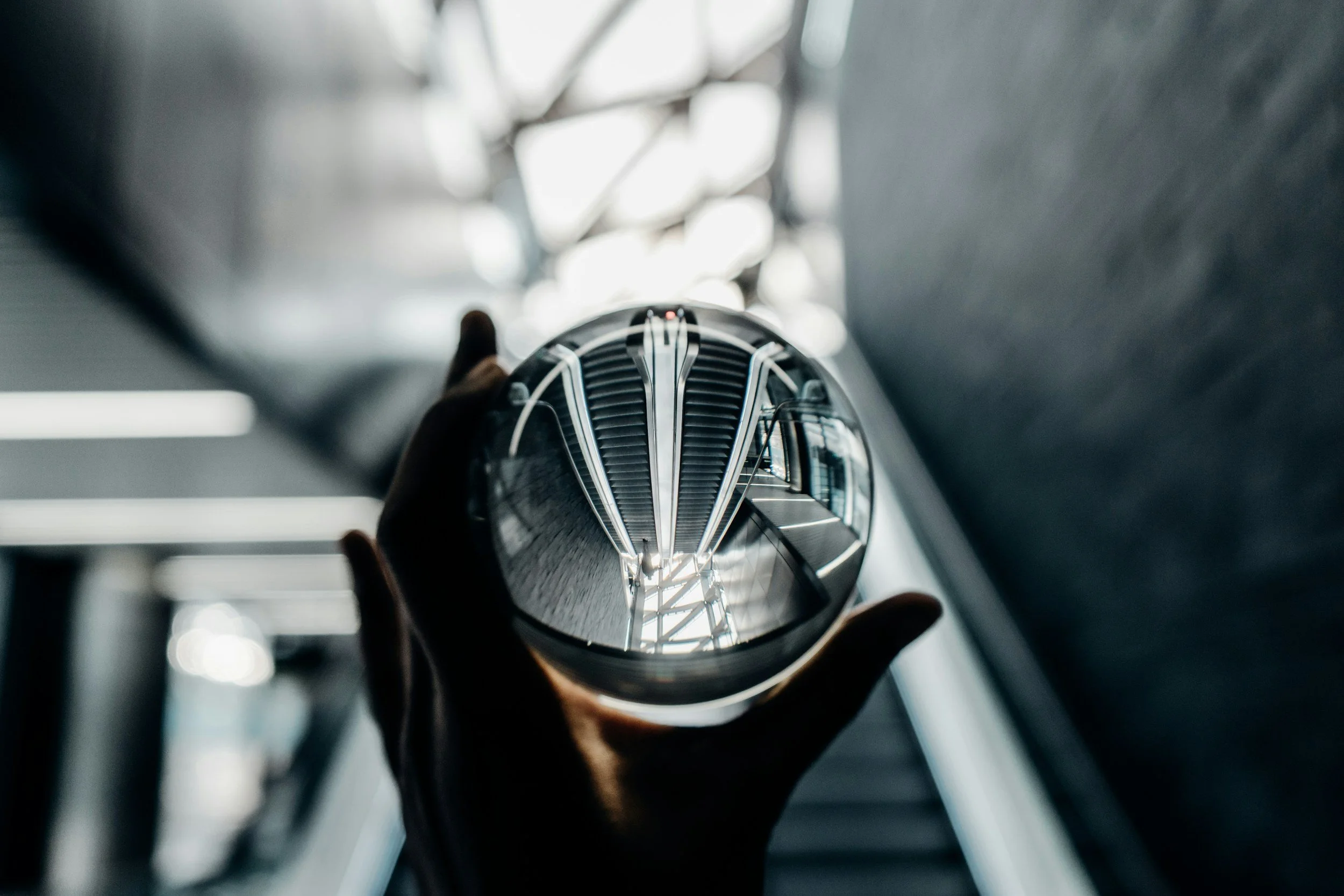 Hand holding a crystal ball with a view of an escalator