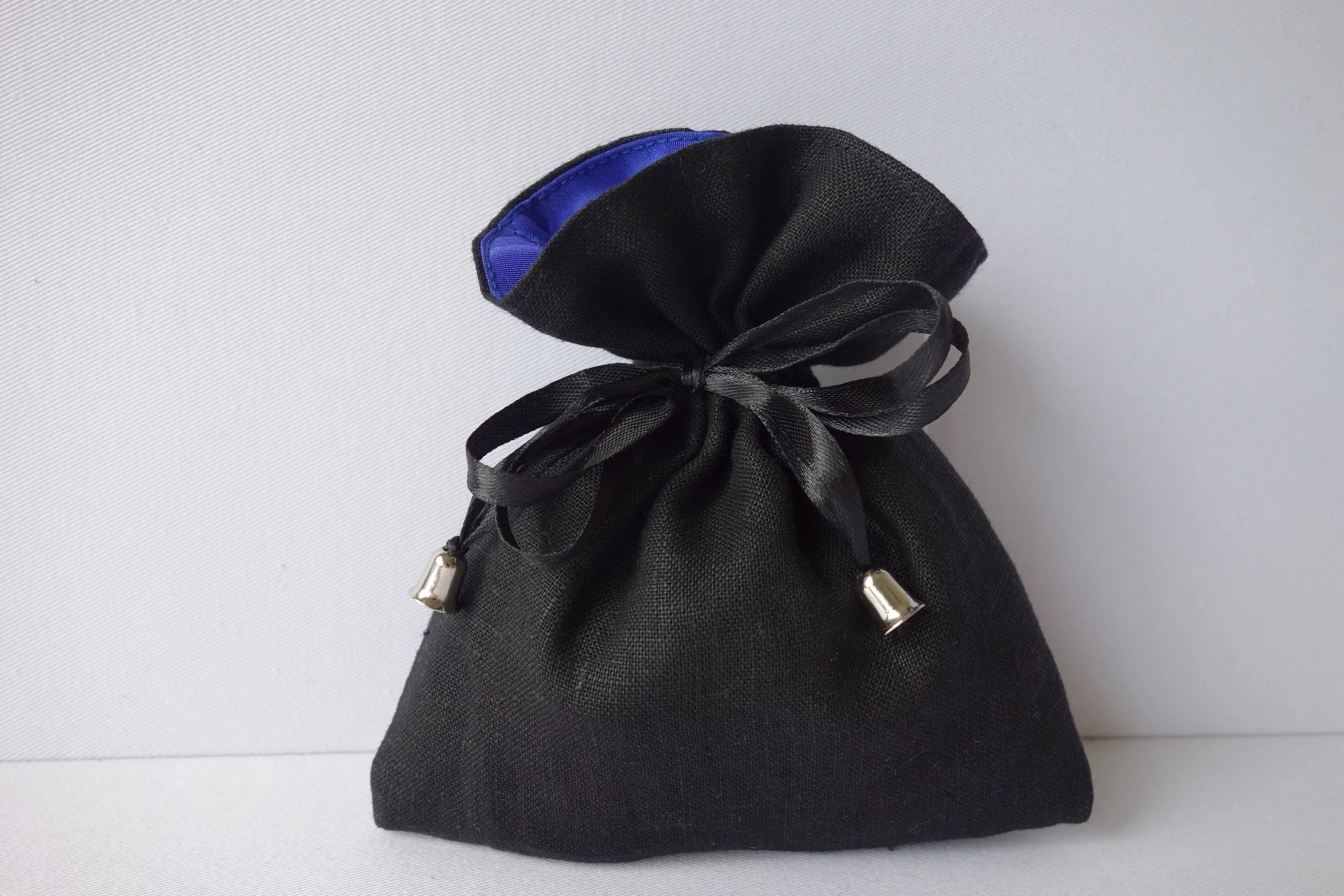 A black drawstring pouch with silver tips on the drawstrings, set against a plain light background.