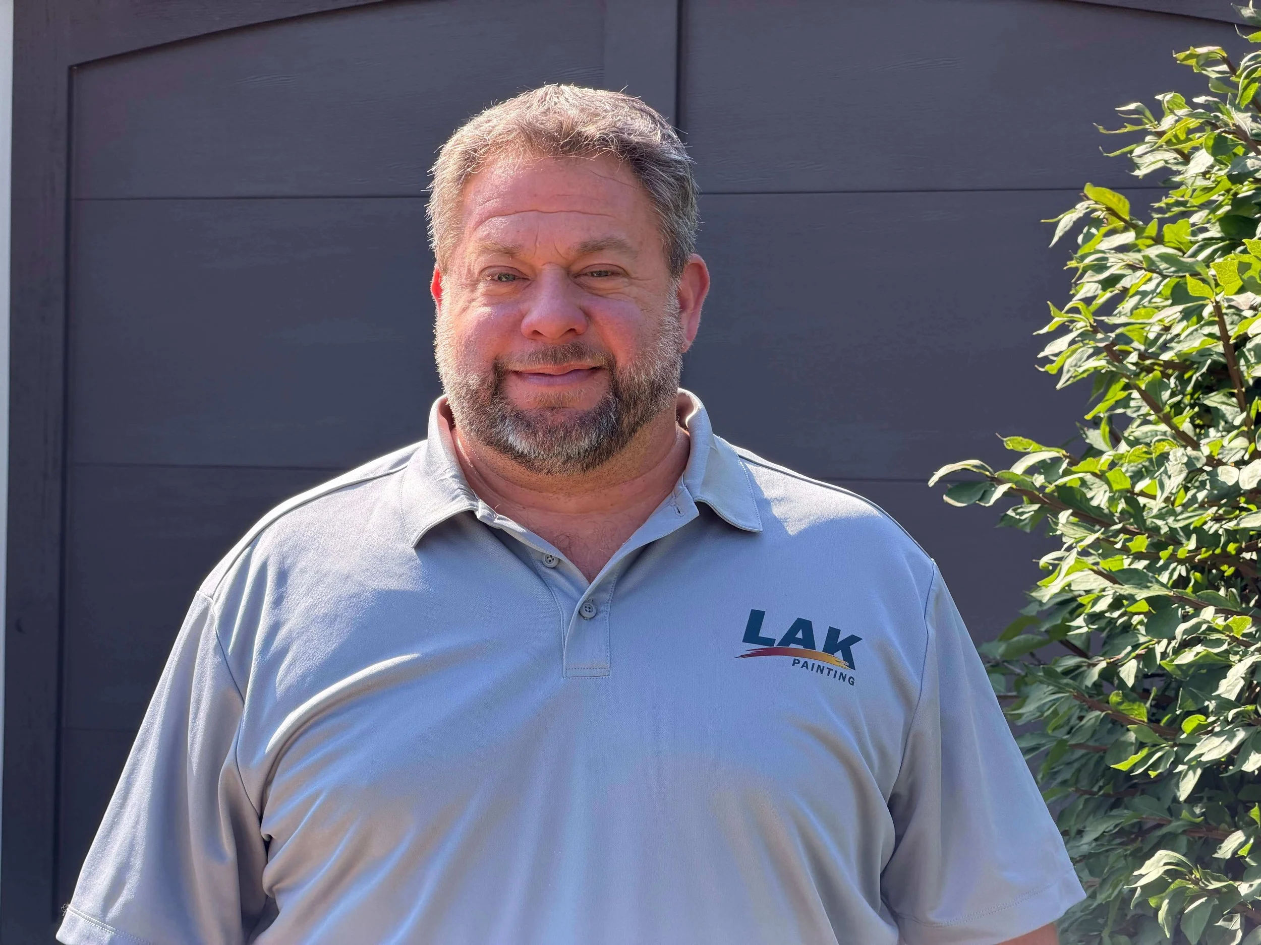 Adam Smith co-owner of LAK Painting smiling outside newly painted home in Kansas City.