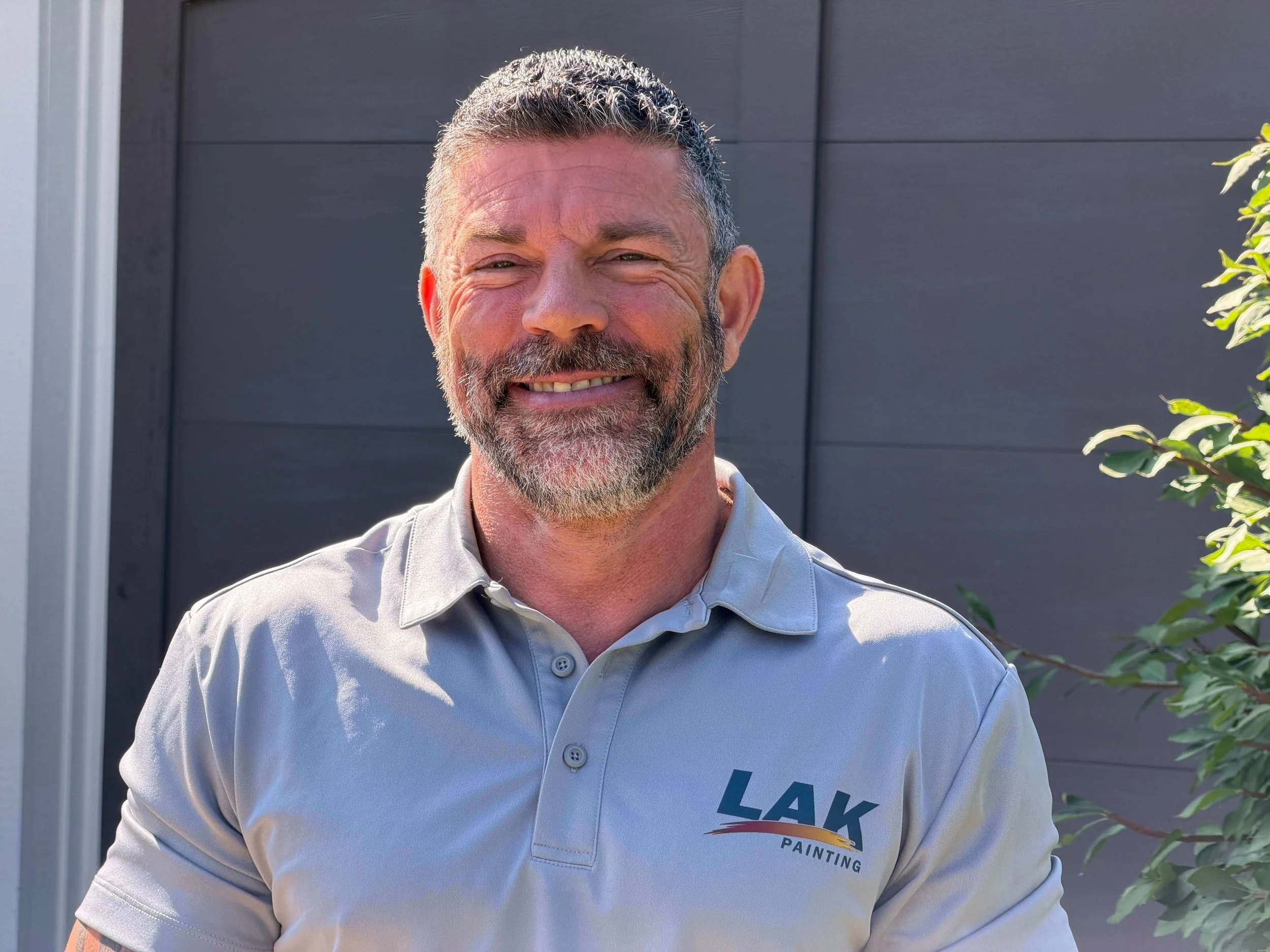 Brian Price owner of LAK Painting smiling outside newly painted home in Kansas City.