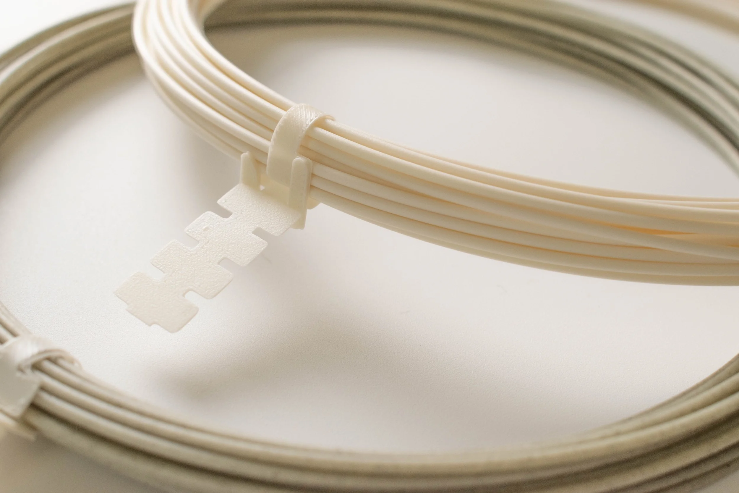 Close-up of Shell White and Seaweed Green trial filament coils with printed retaining clips |