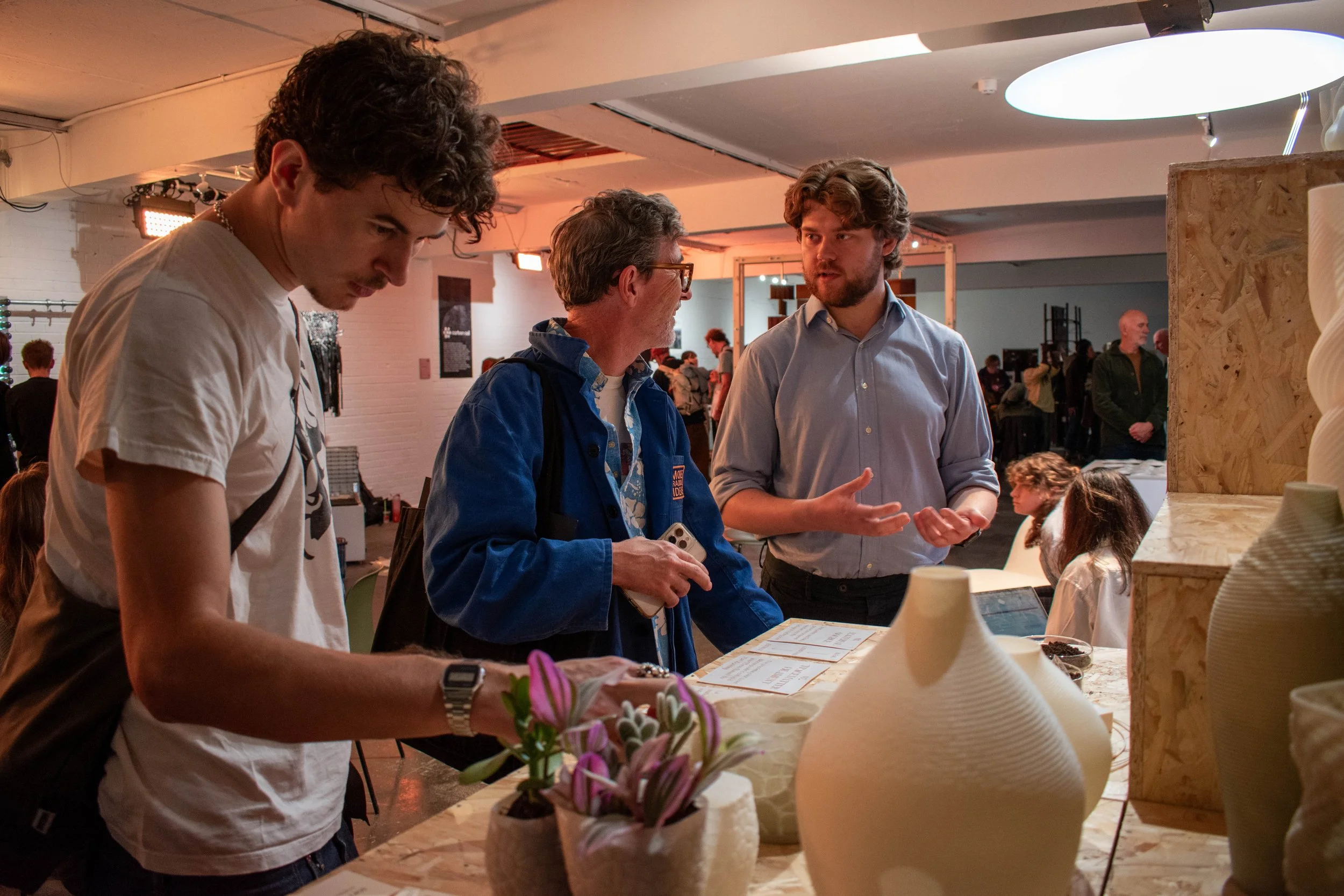 Visitors discuss TraceMatter™ beside 3D-printed vases and plant pots at Material Matters London 2026.