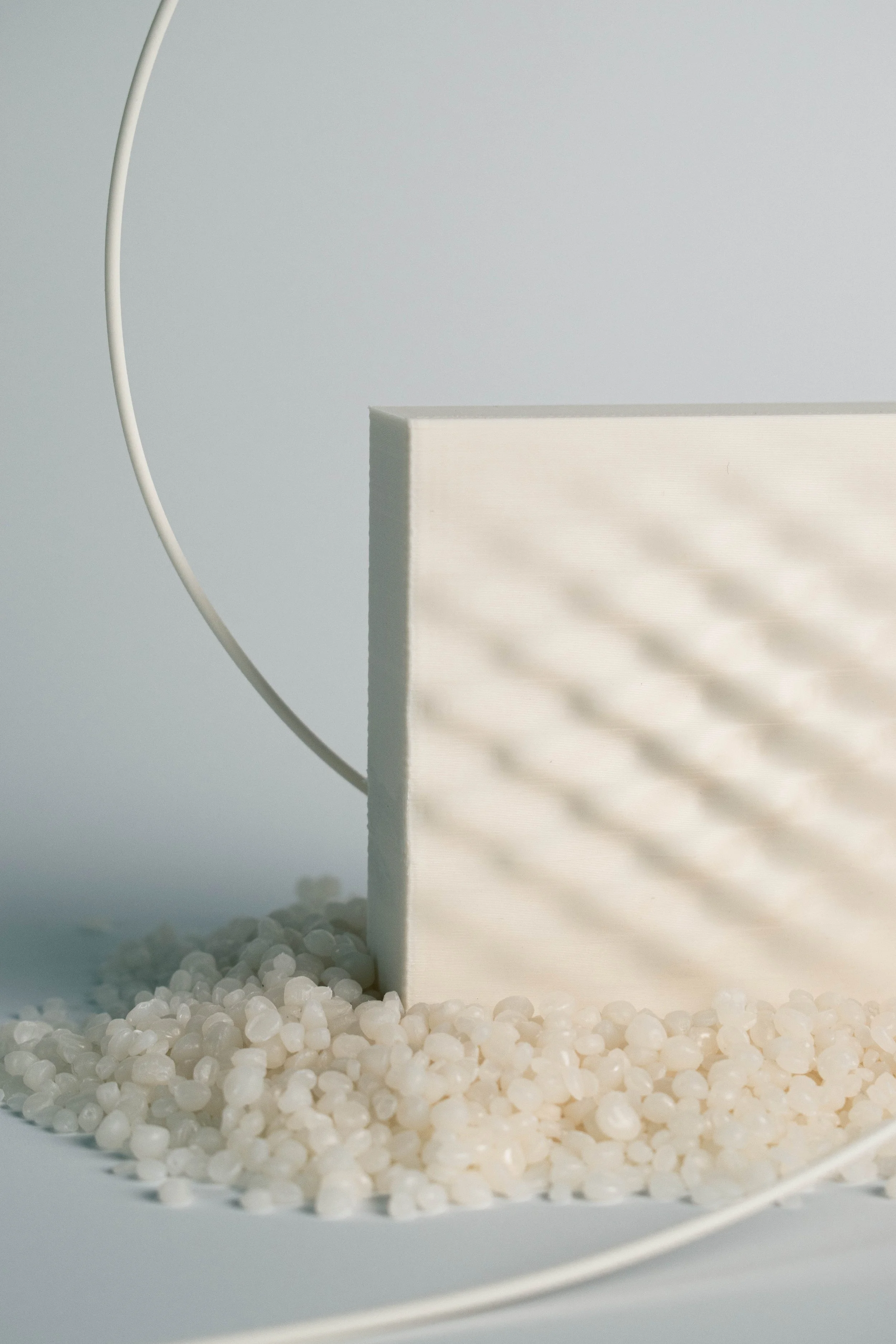 Shell White 3D-printed surface sample with pale material pellets and a loop of filament