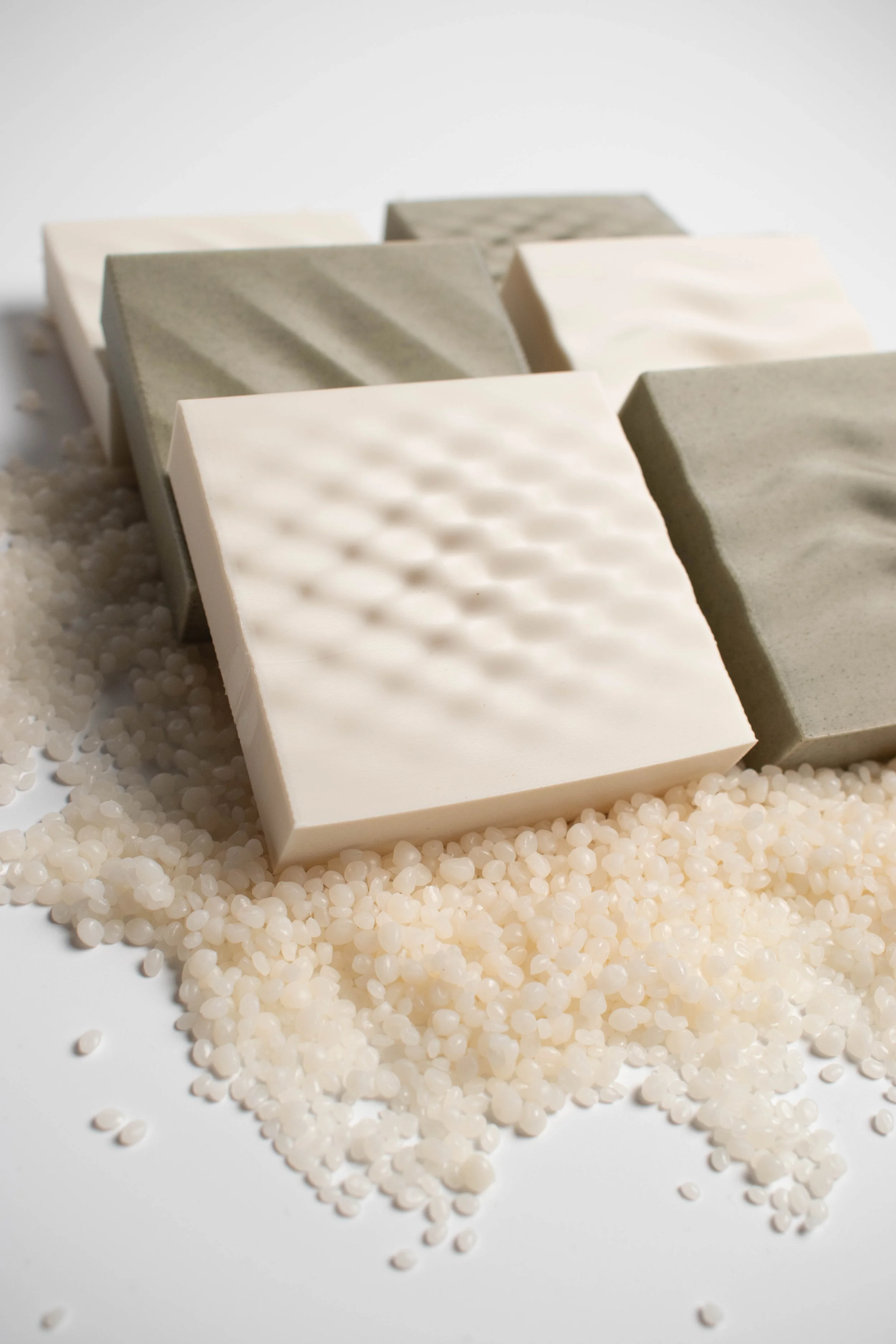 Shell White and Seaweed Green 3D-printed surface samples arranged with pale material pellets