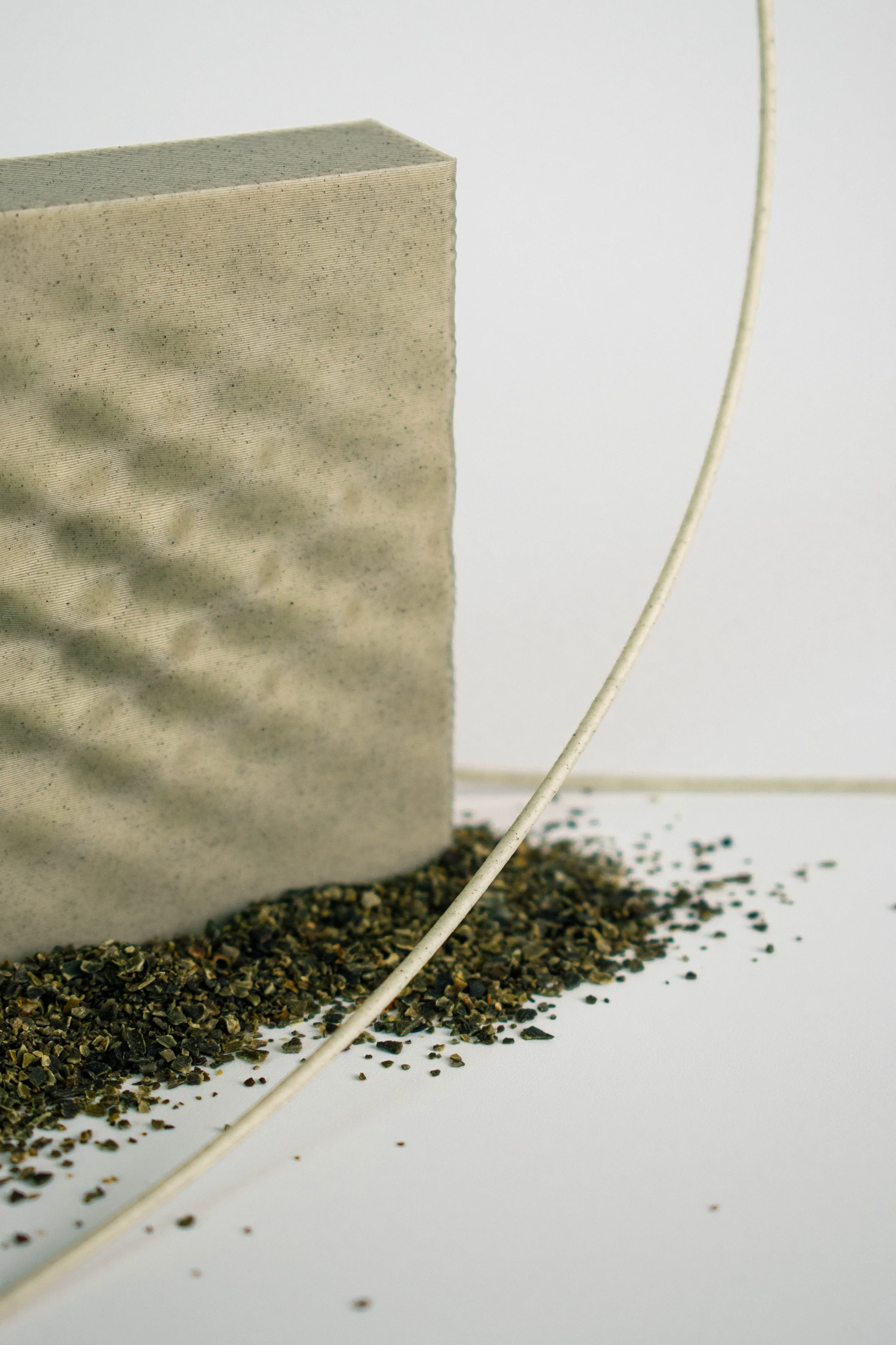Seaweed Green 3D-printed surface sample with seaweed residue and filament in the foreground